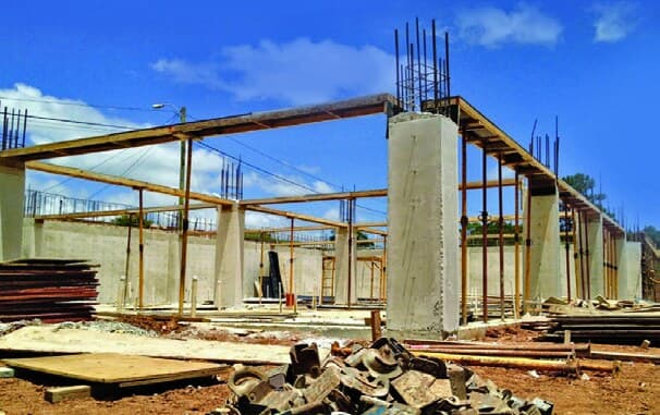 A church building under construction, concrete columns and steel reinforcement against a blue sky